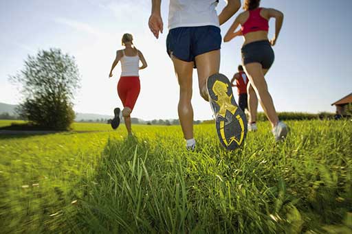 gente con zapatillas de deporte corriendo por la hierba en un día soleado