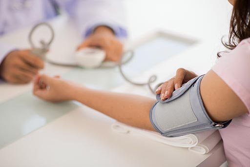 el médico mide la tensión de una mujer con un manguito de presión arterial