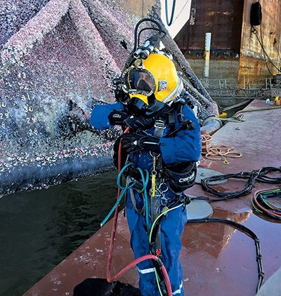 A diver dressed for underwater work in a shipyard
