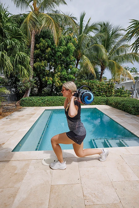 Woman takes a large step forward with her right foot. She lowers body until left knee almost touches the ground.
