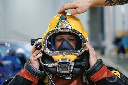A diver dons a dive helmet.