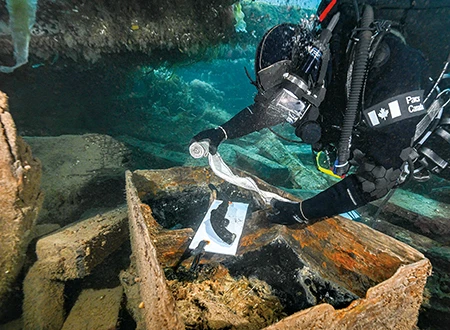 Bernier carefully recovers a pistol from a seamen’s chest on the Erebus. 