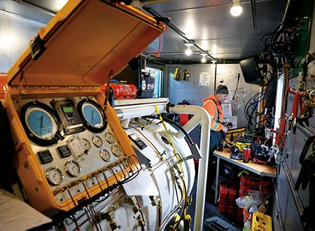 Surface operations aboard the barge include an onsite hyperbaric recompression chamber.