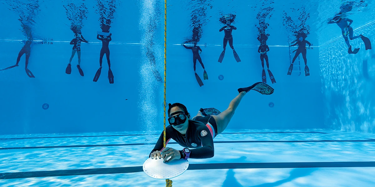 A freediving student performs a static apnea at depth in confined water.
