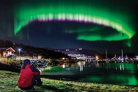 The aurora borealis, or northern lights, dances above the harbor at Skjervoy.