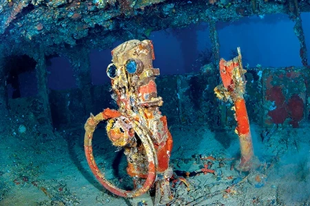 The ship’s wheel and telegraph at the bridge of the Nippo Maru showcases the mix of wartime history and marine ecology